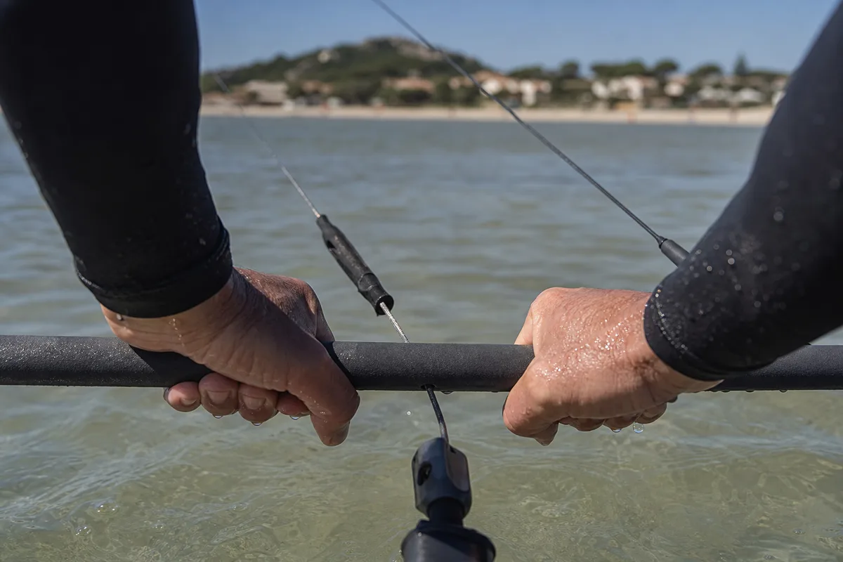 Mains d&rsquo;un pratiquant sur la barre de kitesurf, lignes tendues au-dessus d&rsquo;une lagune peu profonde
