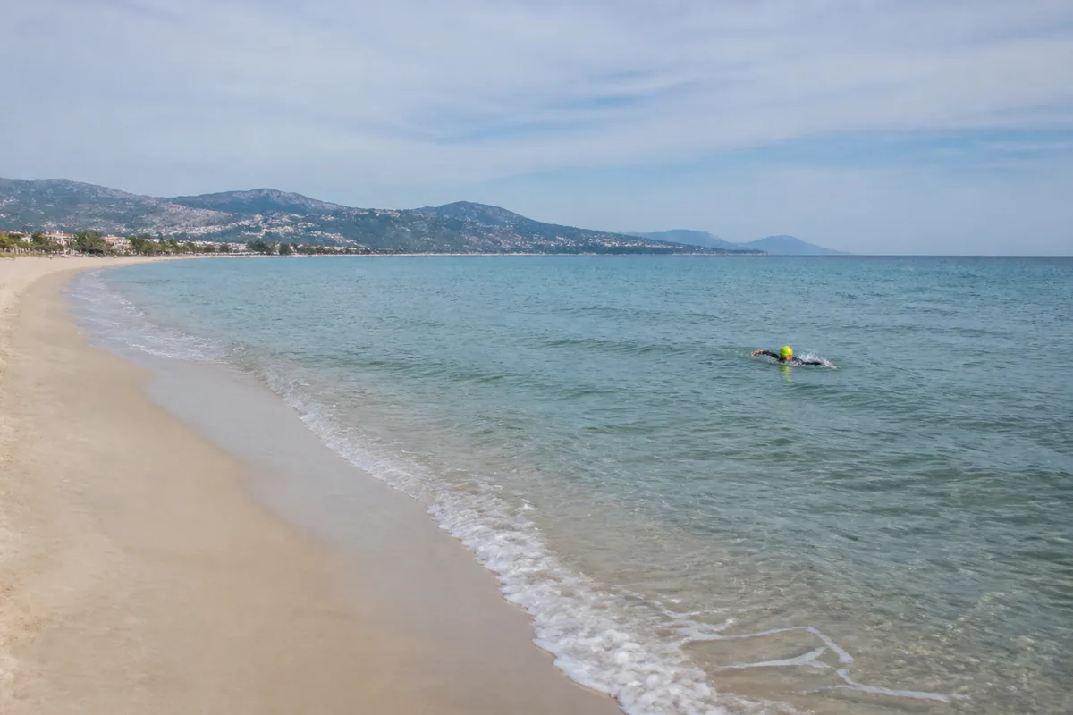 Nageur en combinaison longeant une plage de sable à faible distance du bord